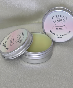 Perfume sólido artesanal aroma jazmín de Creaciones Es Vedra Ibiza en lata de aluminio abierta sobre fondo beige brillante, mostrando su textura cremosa y etiqueta “Hecho a mano en Ibiza”.