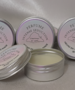 Cuatro latas plateadas de perfume sólido artesanal "Intense Seduction" de Creaciones Es Vedrà, hechas a mano en Ibiza. Una de las latas está abierta mostrando la textura cremosa del perfume, colocadas sobre un fondo suave y satinado.