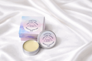 Perfume sólido Velvet Rose hecho a mano en Ibiza, presentado en caja pastel y envase metálico sobre fondo blanco de seda